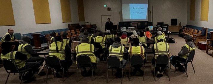 Ed Perez presenting to a room of frontline crew members in high-visibility vests
